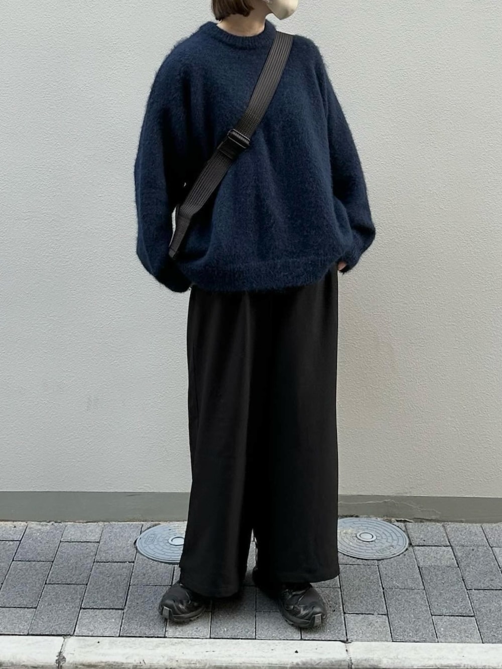 ブルー系のニット/セーター、ブラック系のスラックス、ブラック系のショルダーバッグを着用したレディースの冬コーディネートの2枚目の写真