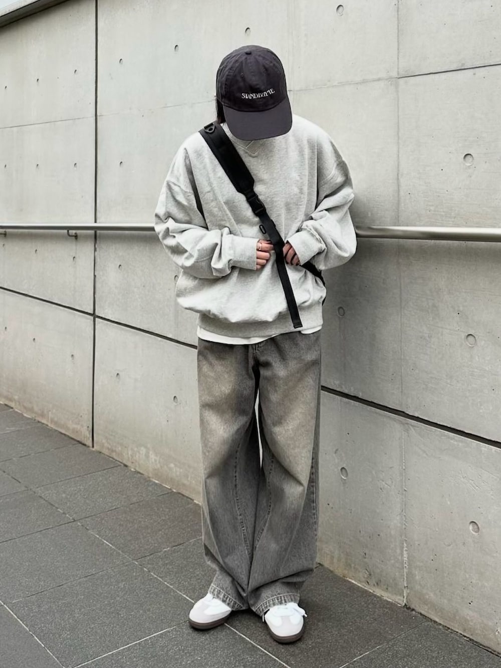 グレー系のスウェット、グレー系のデニムパンツ、ブラック系のショルダーバッグを着用したレディースの秋コーディネートの2枚目の写真