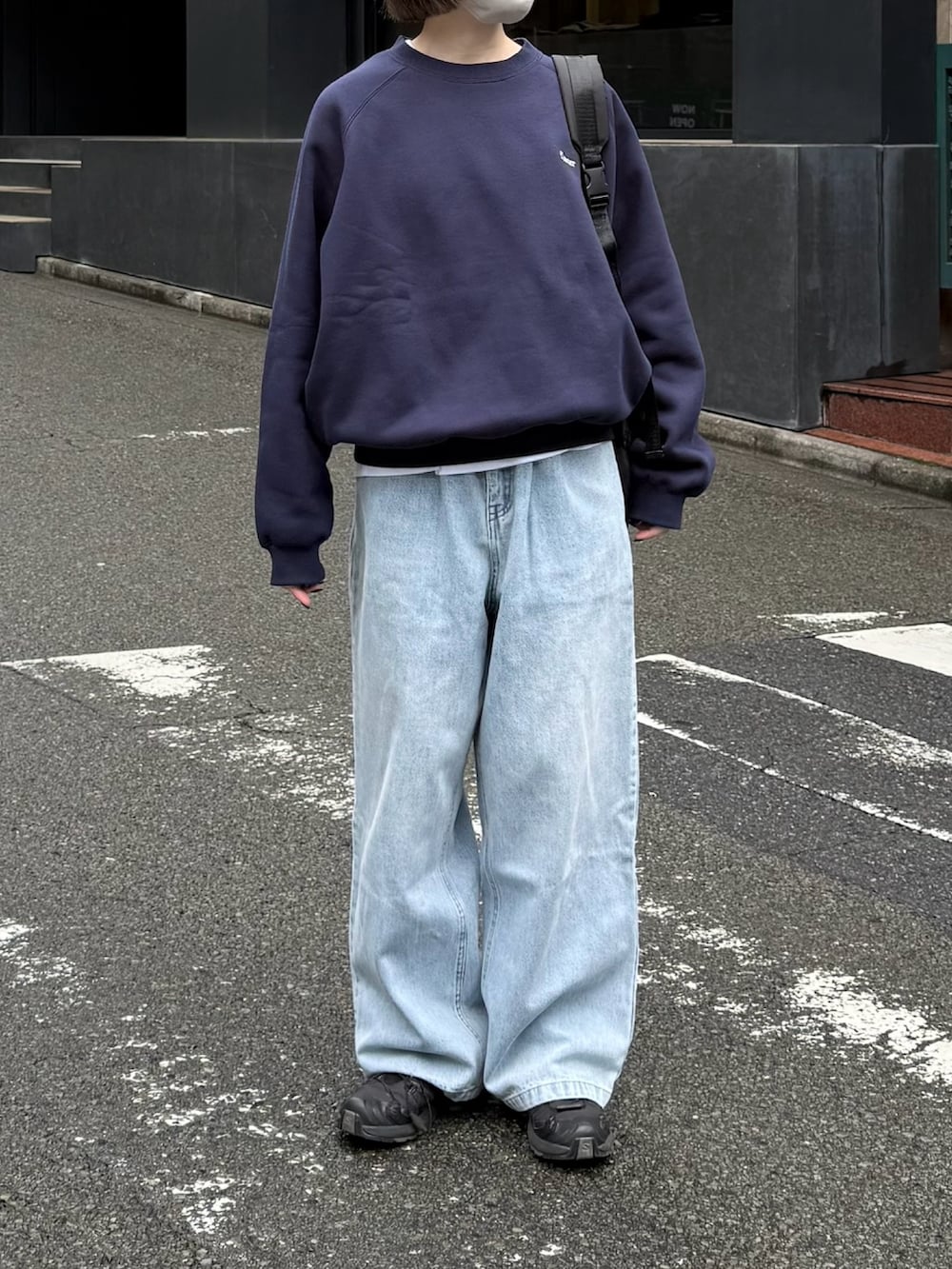 ブラック系のスニーカー、ブルー系のデニムパンツ、ブラック系のショルダーバッグを着用したレディースの秋コーディネートの2枚目の写真