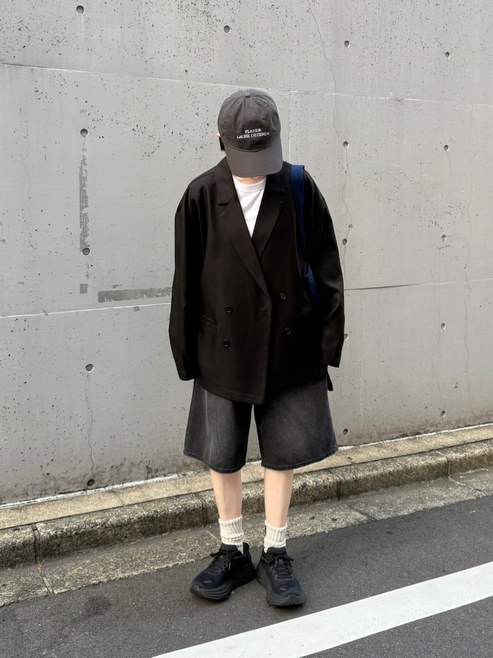 ブラック系のスニーカー、ブラック系のデニムパンツ、ブルー系のトートバッグを着用したレディースの秋コーディネートの2枚目の写真