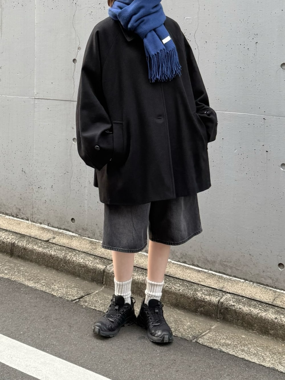 ブラック系のスニーカー、ブラック系のデニムパンツ、ブラック系のステンカラーコートを着用したレディースの秋コーディネートの2枚目の写真