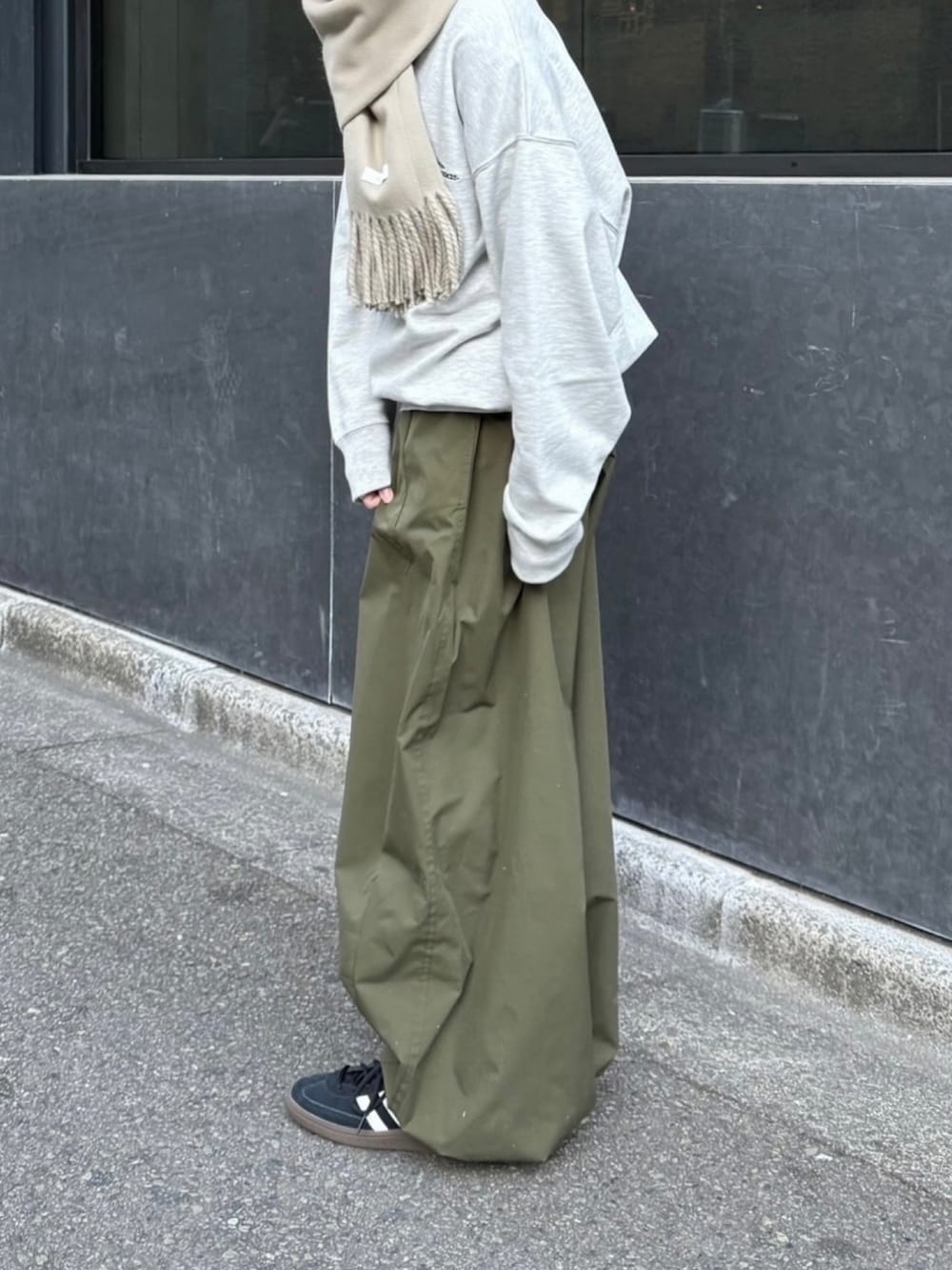 グレー系のスウェット、グリーン系のカーゴパンツ、ブラック系のスニーカーを着用したレディースの冬コーディネートの2枚目の写真