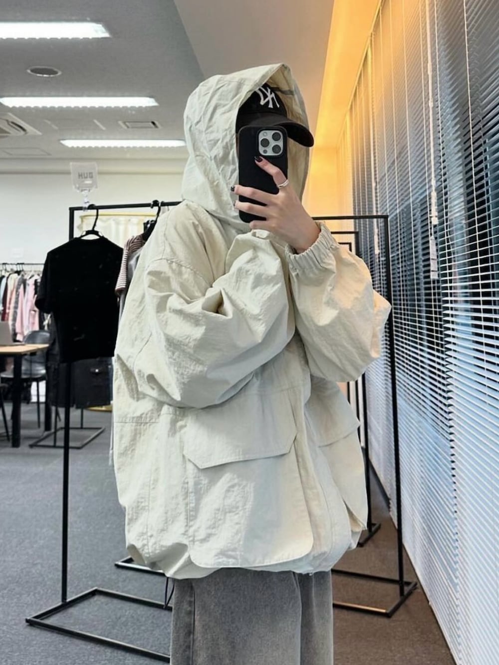 ホワイト系のマウンテンパーカー、グレー系のデニムパンツ、ブラック系のショルダーバッグを着用したレディースの秋コーディネートの3枚目の写真