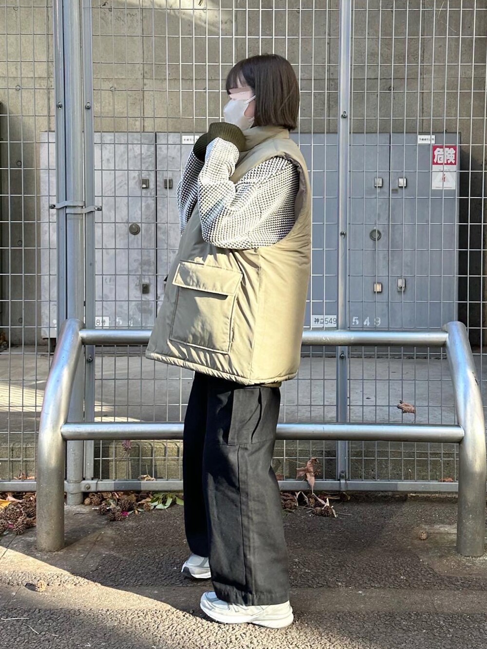 ベージュ系のベスト、グリーン系のニット/セーター、ブラック系のカーゴパンツを着用したレディースの冬コーディネートの2枚目の写真