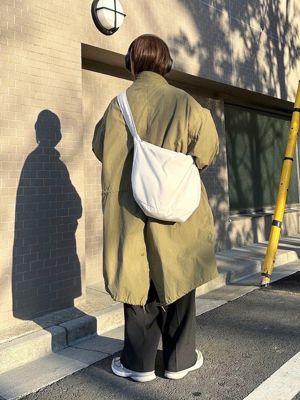 グリーン系のモッズコート、ブラウン系のニット/セーター、ブラック系のスラックスを着用したレディースの春コーディネートの3枚目の写真