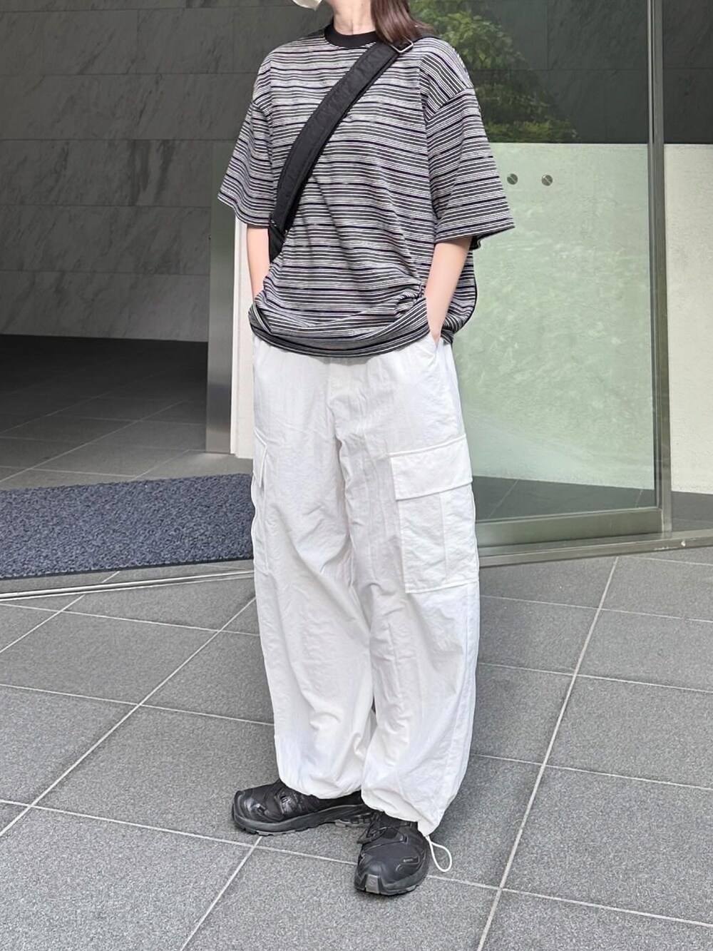 ブラック系のTシャツ/カットソー、ホワイト系のカーゴパンツ、ブラック系のショルダーバッグを着用したレディースの夏コーディネートの2枚目の写真