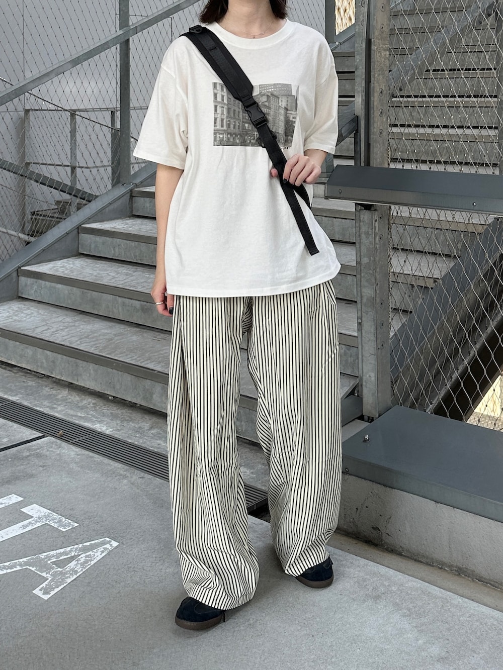 ホワイト系のTシャツ/カットソー、ブラック系のショルダーバッグ、ブラック系のスニーカーを着用したレディースの夏コーディネートの2枚目の写真