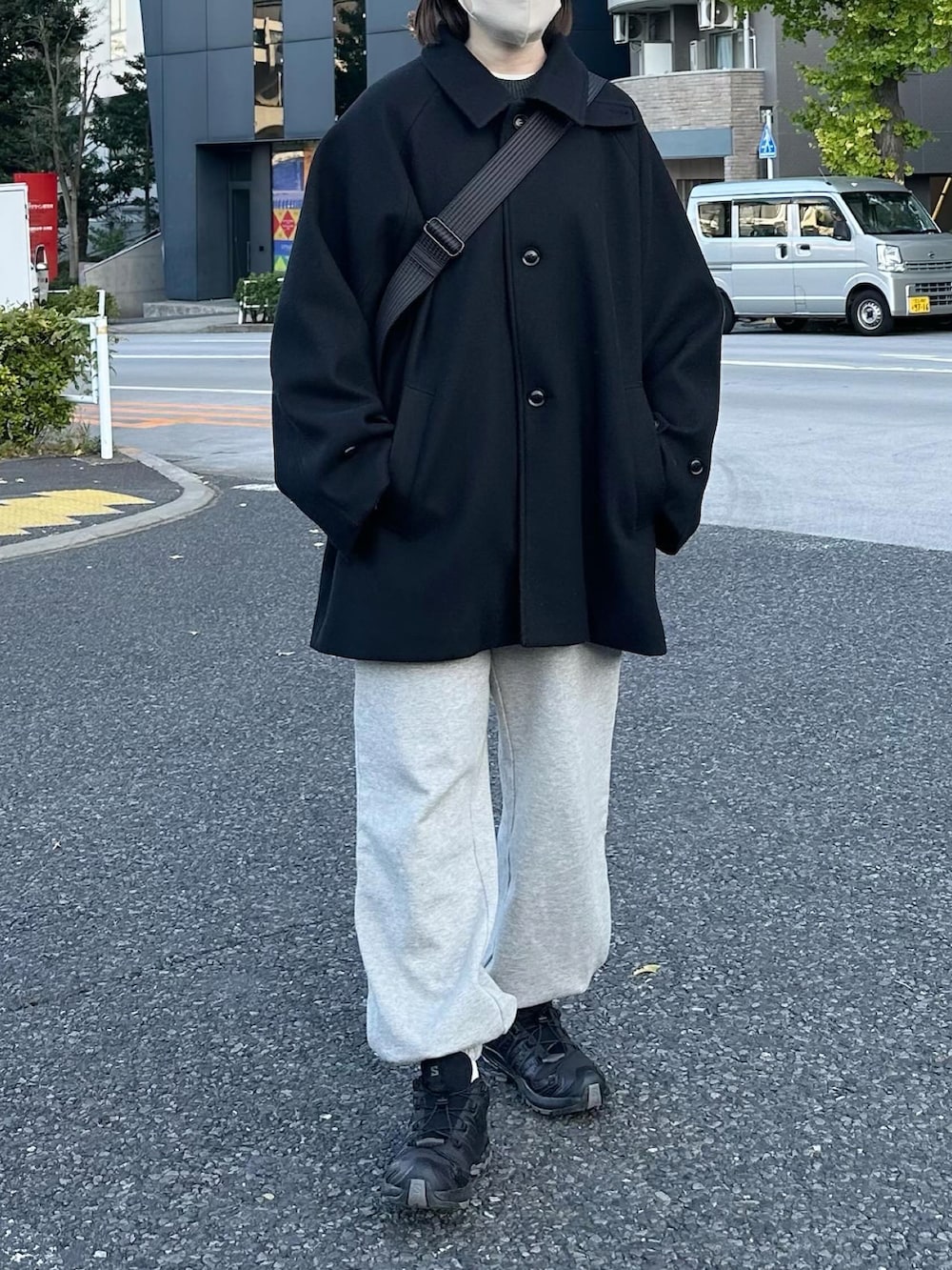 ブラック系のステンカラーコート、グレー系のスウェットパンツ、ブラック系のショルダーバッグを着用したレディースの秋コーディネートの2枚目の写真