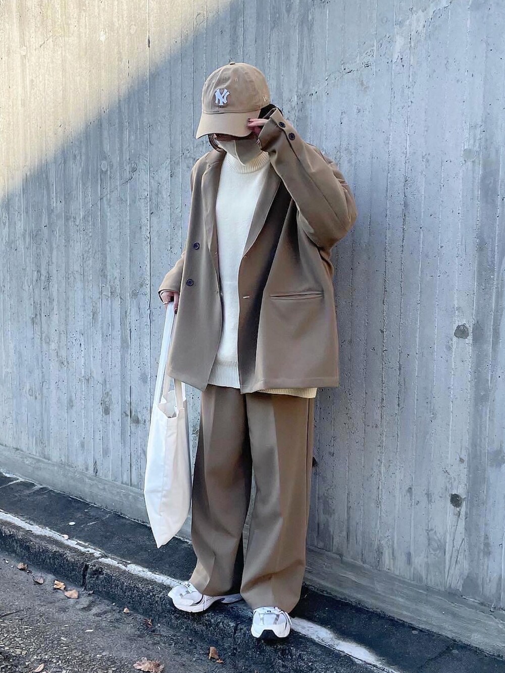 ベージュ系のテーラードジャケット、ベージュ系のニット/セーター、ホワイト系のトートバッグを着用したレディースの冬コーディネートの2枚目の写真