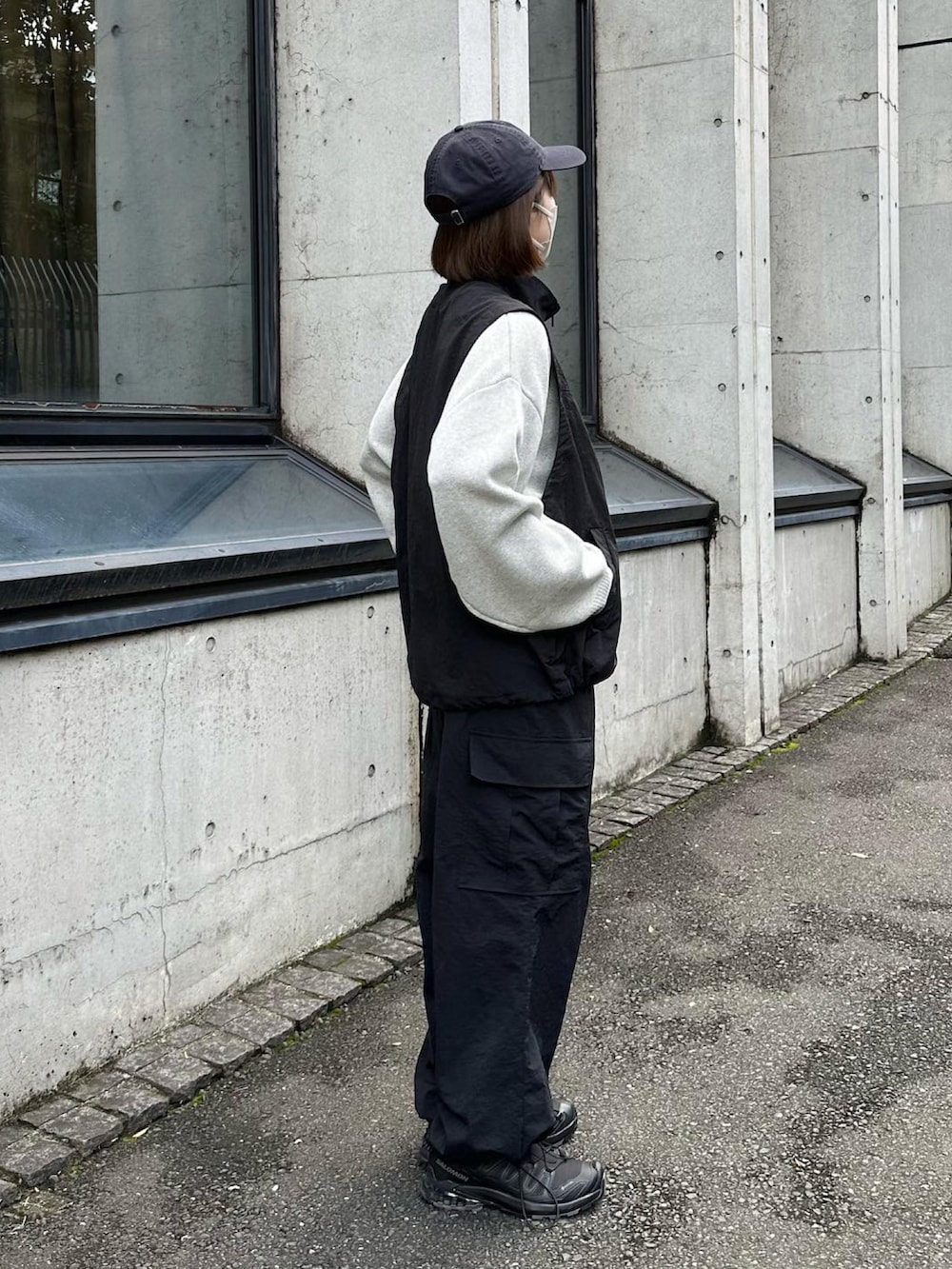 グレー系のニット/セーター、ブラック系のベスト、ブラック系のカーゴパンツを着用したレディースの秋コーディネートの2枚目の写真