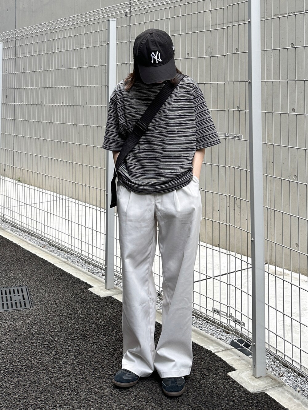 ブラック系のTシャツ/カットソー、ホワイト系のチノパンツ、ブラック系のショルダーバッグを着用したレディースの夏コーディネートの2枚目の写真