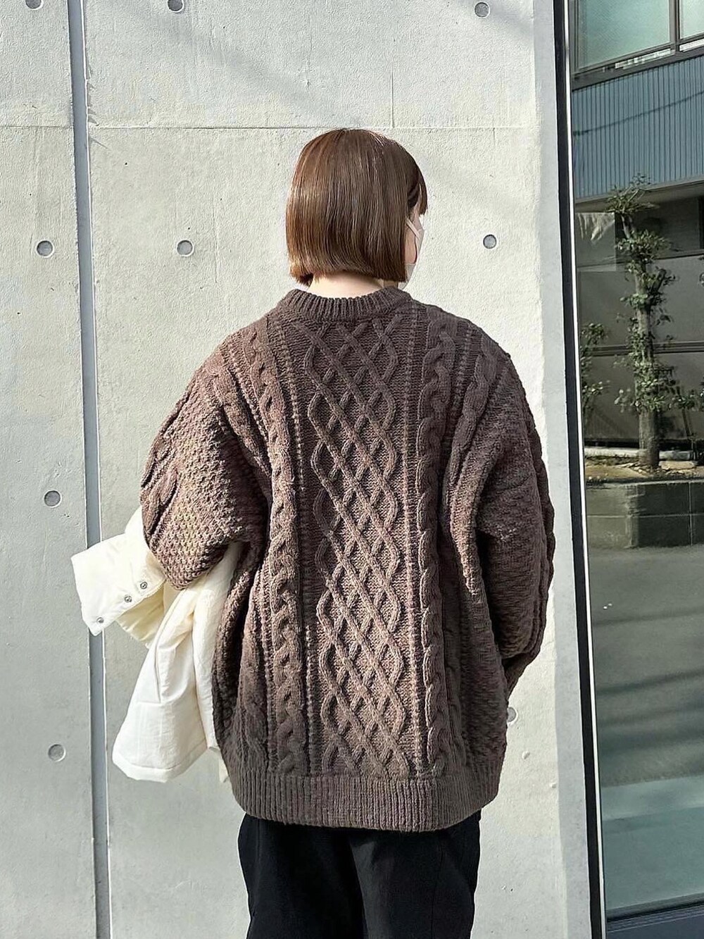 ブラウン系のニット/セーター、ブラック系のカーゴパンツ、ホワイト系のその他アウターを着用したレディースの冬コーディネートの2枚目の写真