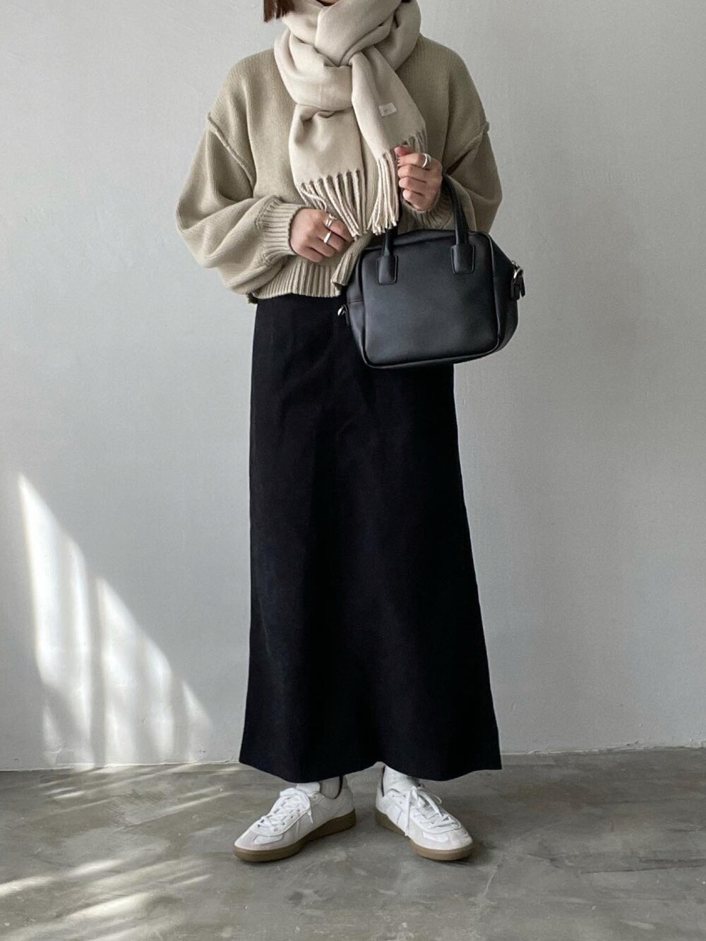 ベージュ系のニット/セーター、ブラック系のスカート、ブラック系のハンドバッグを着用したレディースの秋コーディネートの2枚目の写真