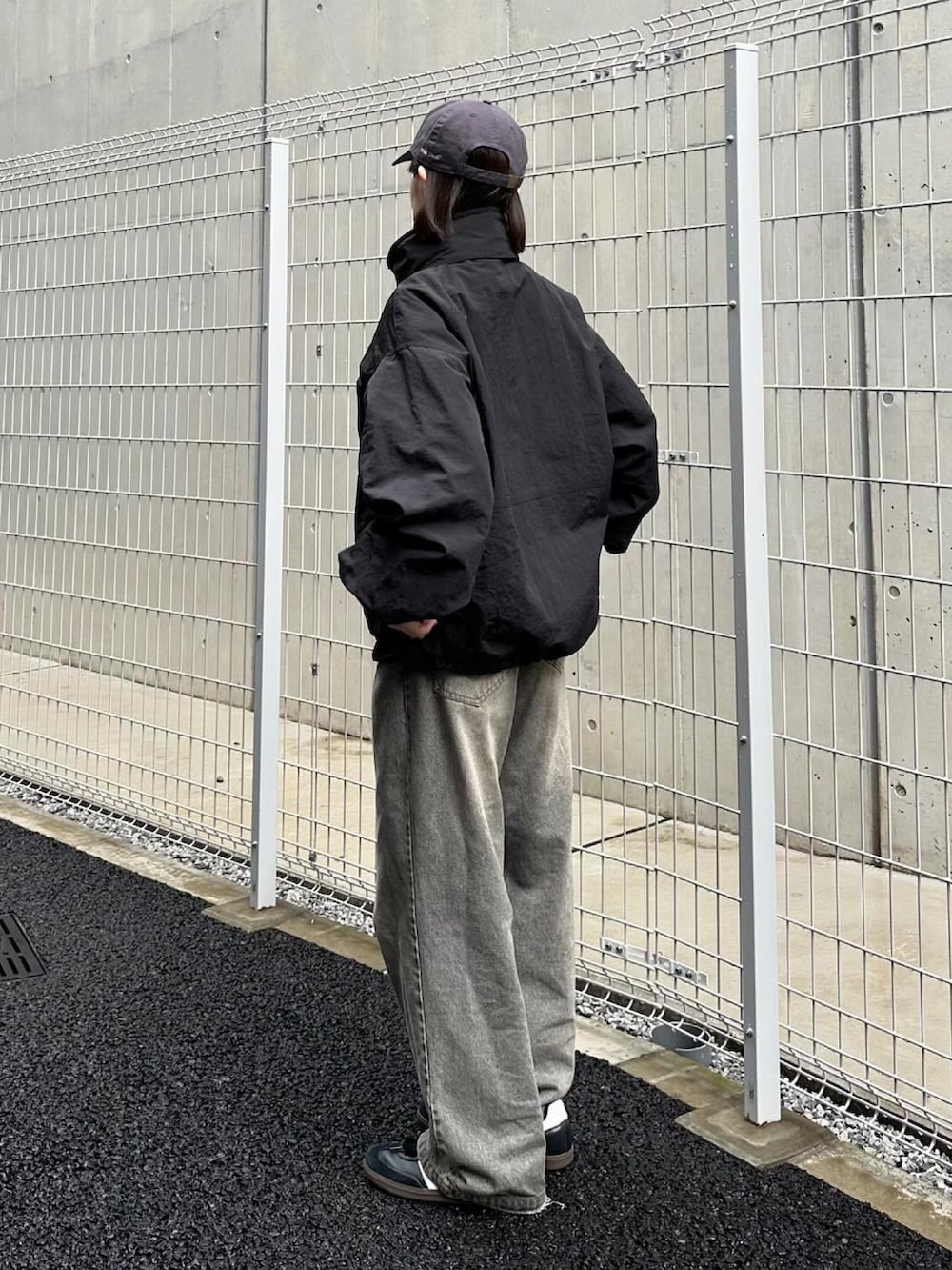 ブラック系のマウンテンパーカー、グレー系のデニムパンツ、ブラック系のスニーカーを着用したレディースの秋コーディネートの3枚目の写真