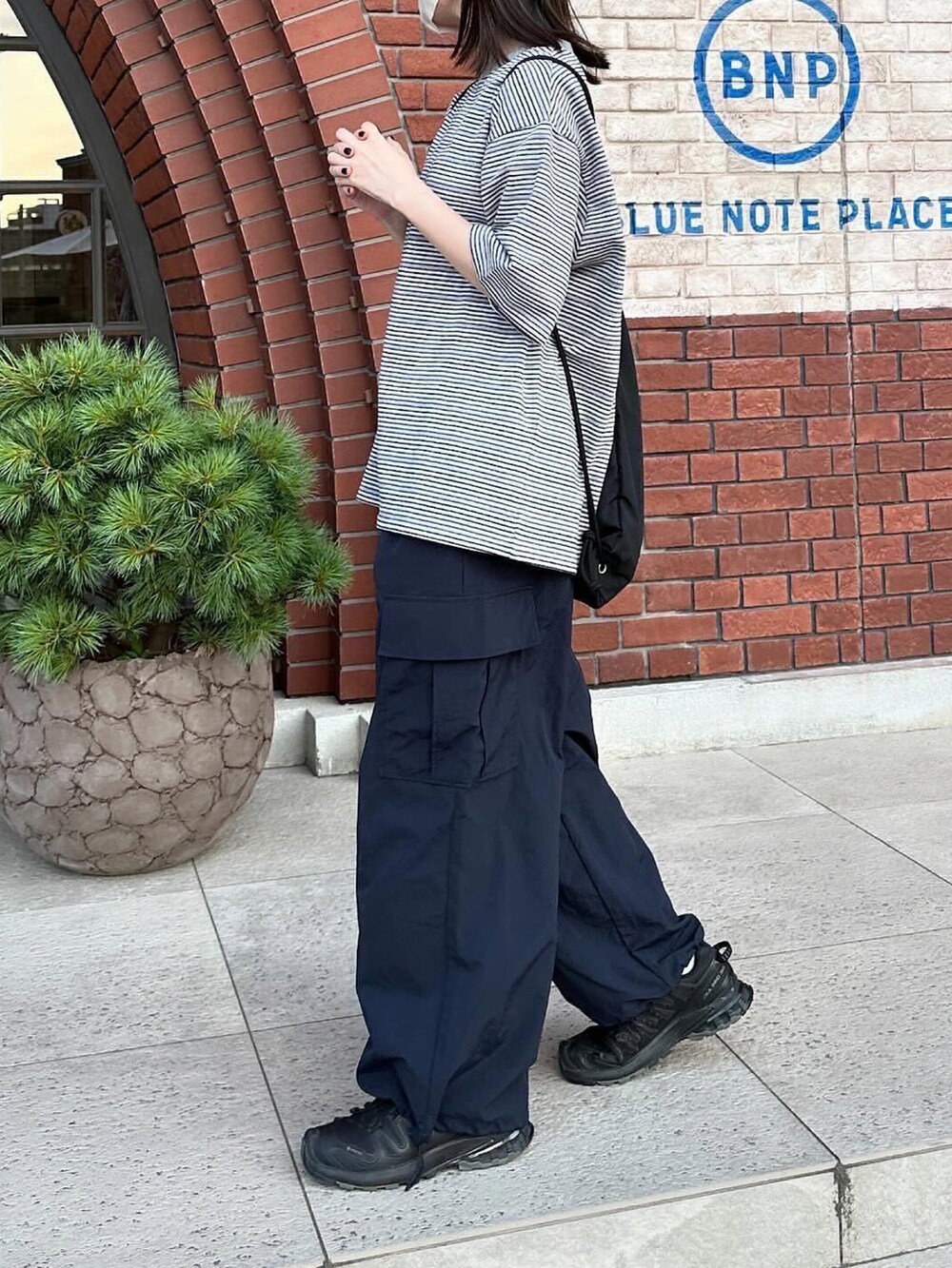 グレー系のTシャツ/カットソー、ブルー系のカーゴパンツ、ブラック系のショルダーバッグを着用したレディースの夏コーディネートの2枚目の写真