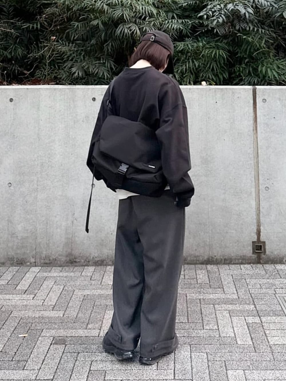 ブラック系のスウェット、グレー系のスラックス、ブラック系のショルダーバッグを着用したレディースの春コーディネートの2枚目の写真