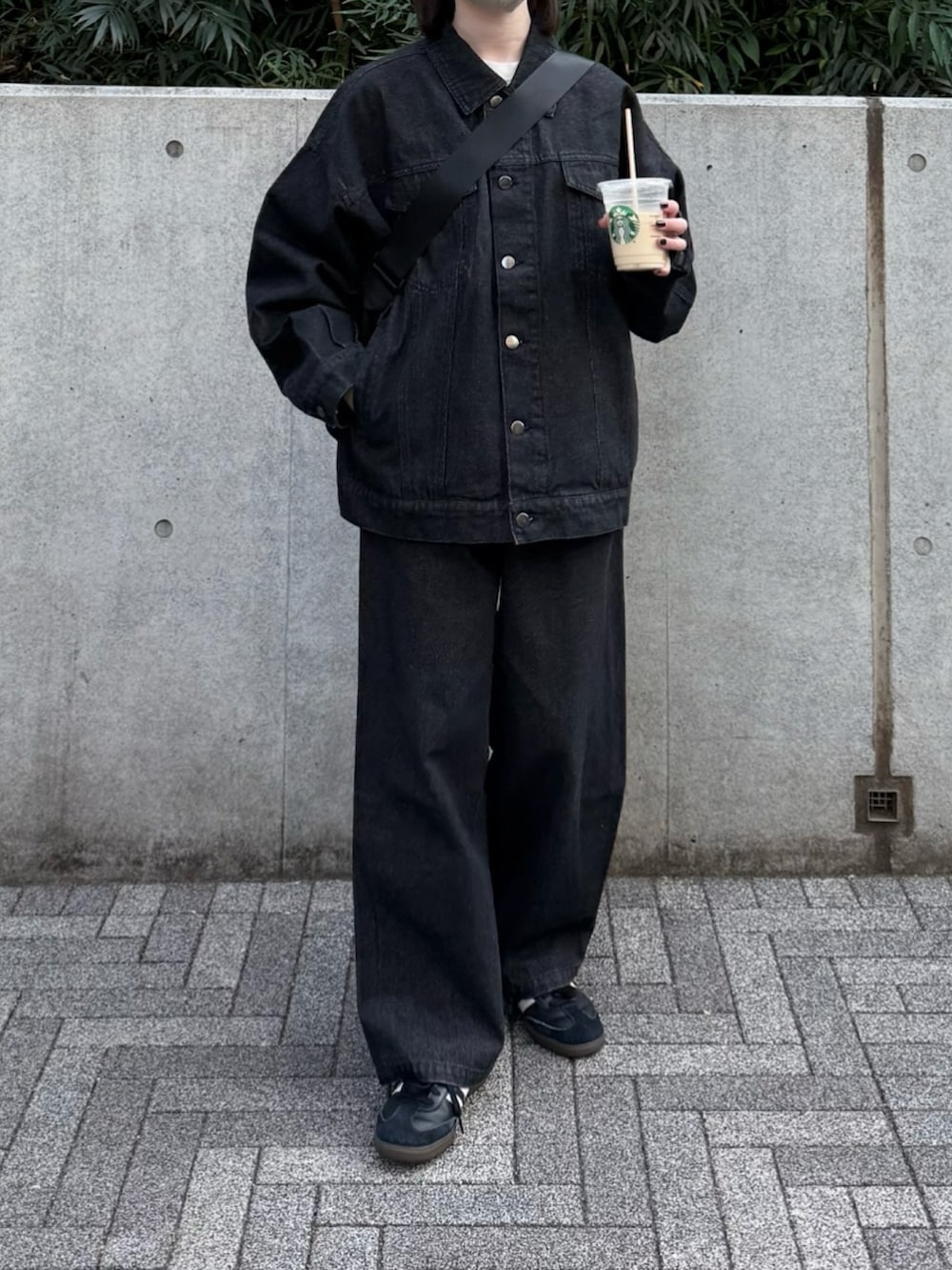 ブラック系のデニムジャケット、ブラック系のデニムパンツ、ブラック系のスニーカーを着用したレディースの春コーディネートの2枚目の写真