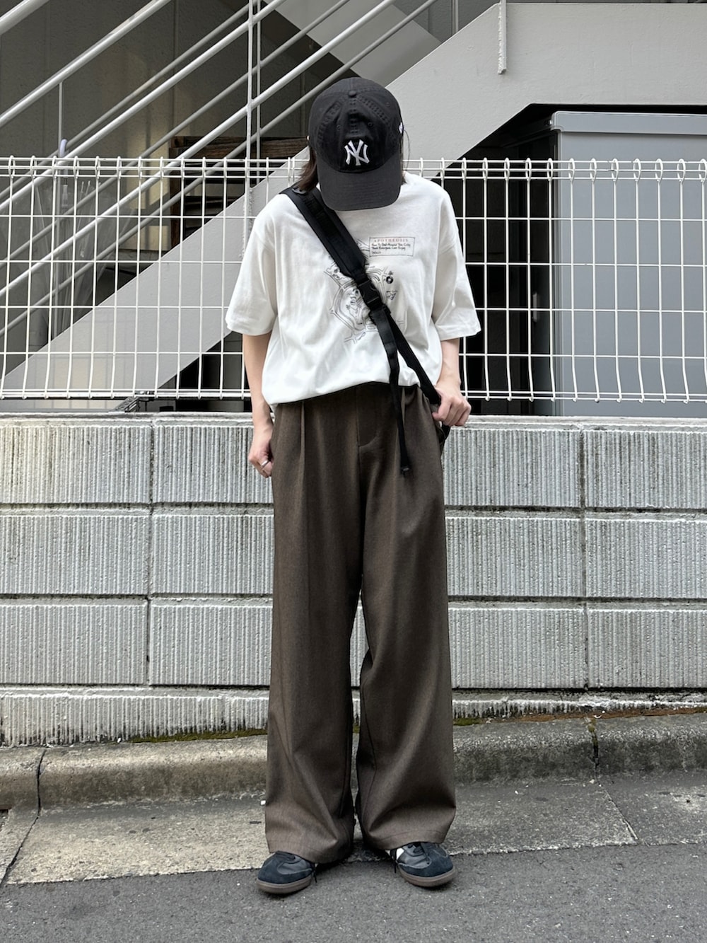 ホワイト系のTシャツ/カットソー、ブラウン系のスラックス、ブラック系のショルダーバッグを着用したレディースの夏コーディネートの2枚目の写真