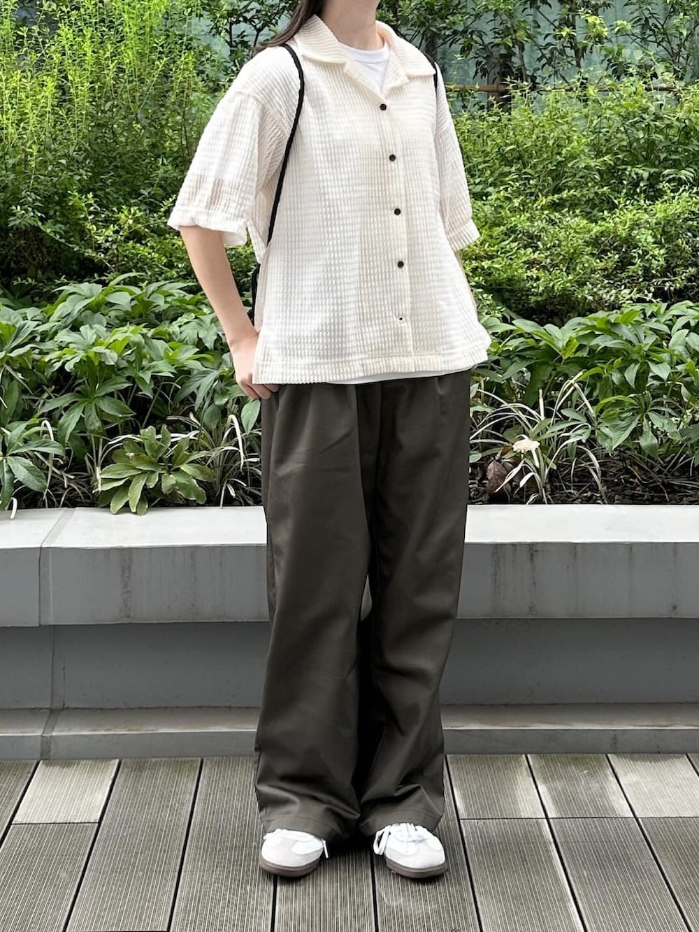 ホワイト系のシャツ/ブラウス、ブラウン系のチノパンツ、ブラック系のショルダーバッグを着用したレディースの夏コーディネートの2枚目の写真