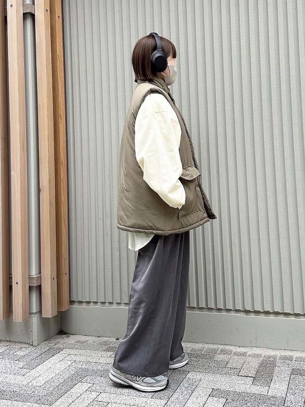 ベージュ系のベスト、イエロー系のシャツ/ブラウス、グレー系のスラックスを着用したレディースの春コーディネートの2枚目の写真