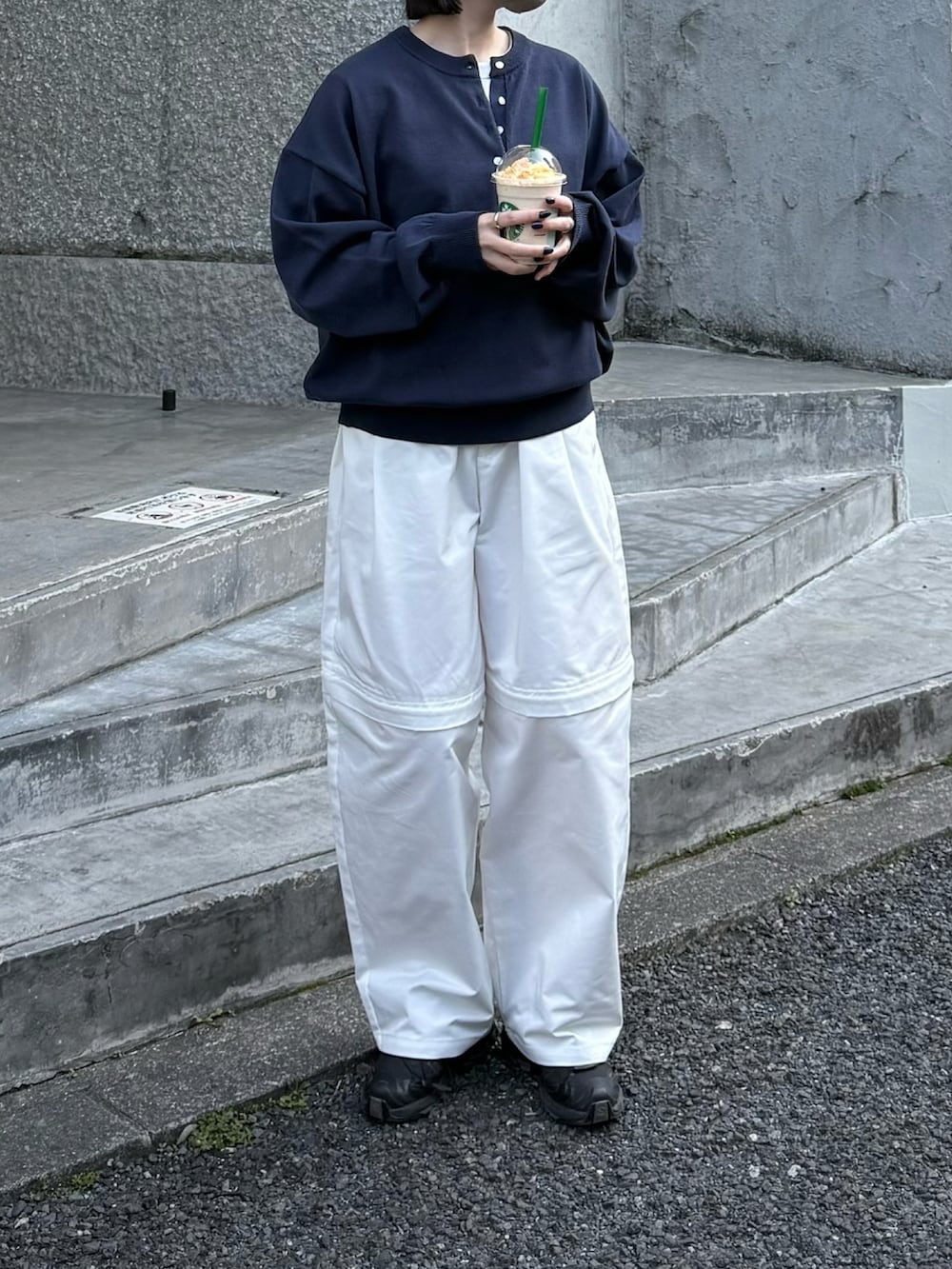 ブラック系のスニーカー、ブルー系のニット/セーター、ホワイト系のその他パンツを着用したレディースの春コーディネートの2枚目の写真