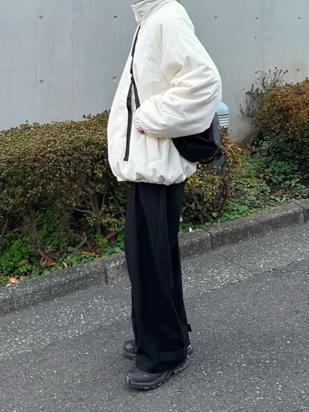 ホワイト系のその他アウター、ブラック系のスラックス、ブラック系のショルダーバッグを着用したレディースの冬コーディネートの2枚目の写真