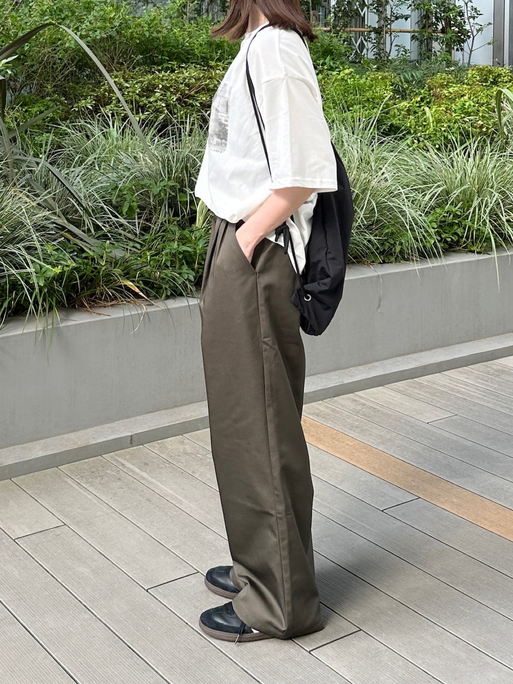 ホワイト系のTシャツ/カットソー、ブラウン系のチノパンツ、ブラック系のショルダーバッグを着用したレディースの夏コーディネートの3枚目の写真