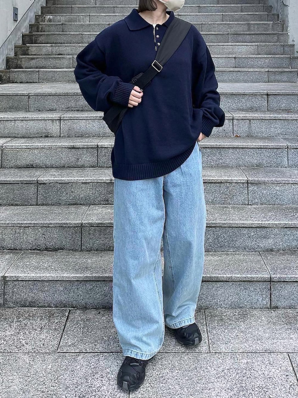 ブルー系のポロシャツ、ブルー系のデニムパンツ、ブラック系のスニーカーを着用したレディースの秋コーディネートの2枚目の写真