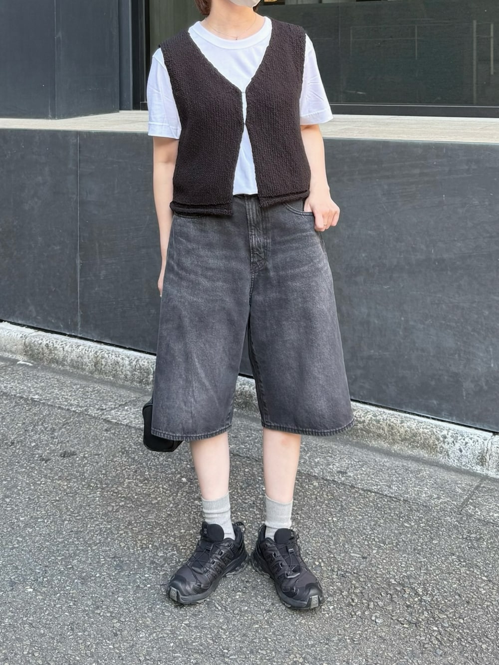 ブラック系のスニーカー、ブラック系のベスト、ブラック系のデニムパンツを着用したレディースの夏コーディネートの2枚目の写真