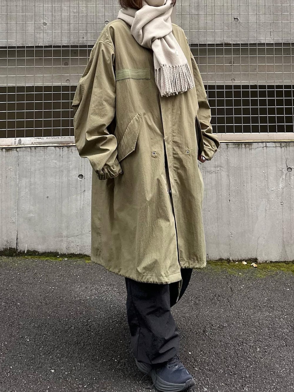 グリーン系のモッズコート、ブラック系のカーゴパンツ、ブラック系のスニーカーを着用したレディースの秋コーディネートの2枚目の写真