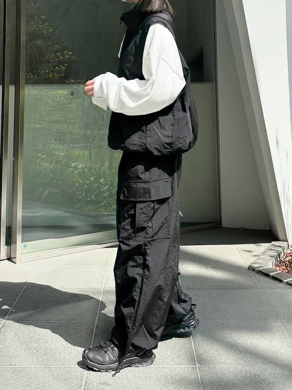ブラック系のベスト、ホワイト系のTシャツ/カットソー、ブラック系のカーゴパンツを着用したレディースの春コーディネートの2枚目の写真