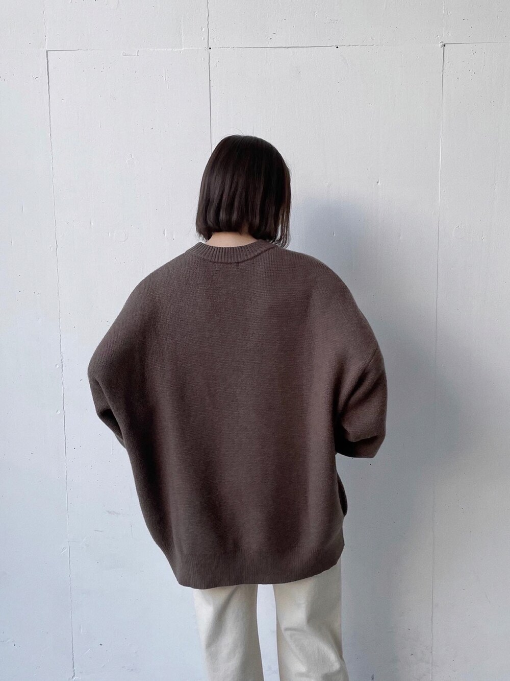 ホワイト系のデニムパンツ、ブラック系のスニーカー、ブラウン系のニット/セーターを着用したレディースの秋コーディネートの3枚目の写真