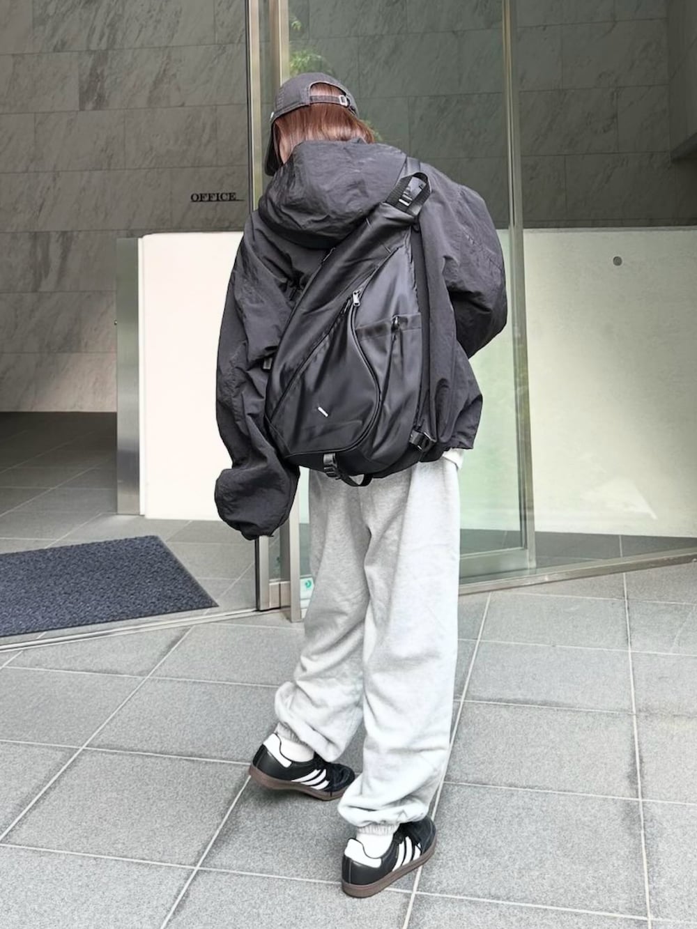 ブラック系のパーカー、グレー系のスウェットパンツ、ブラック系のショルダーバッグを着用したレディースの秋コーディネートの2枚目の写真