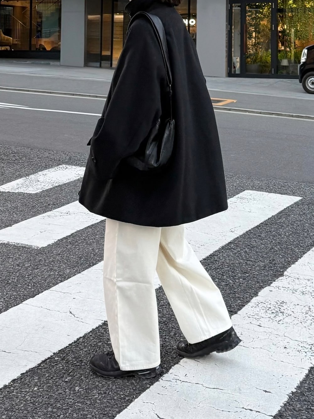ブラック系のスニーカー、ホワイト系のその他パンツ、ブラック系のステンカラーコートを着用したレディースの冬コーディネートの2枚目の写真