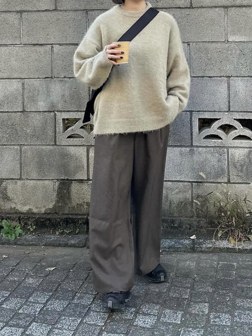 ベージュ系のニット/セーター、ブラウン系のスラックス、ブラック系のショルダーバッグを着用したレディースの冬コーディネートの2枚目の写真