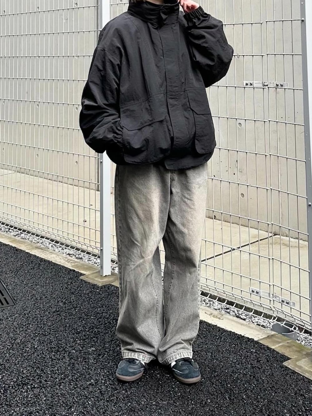 ブラック系のマウンテンパーカー、グレー系のデニムパンツ、ブラック系のスニーカーを着用したレディースの秋コーディネートの2枚目の写真