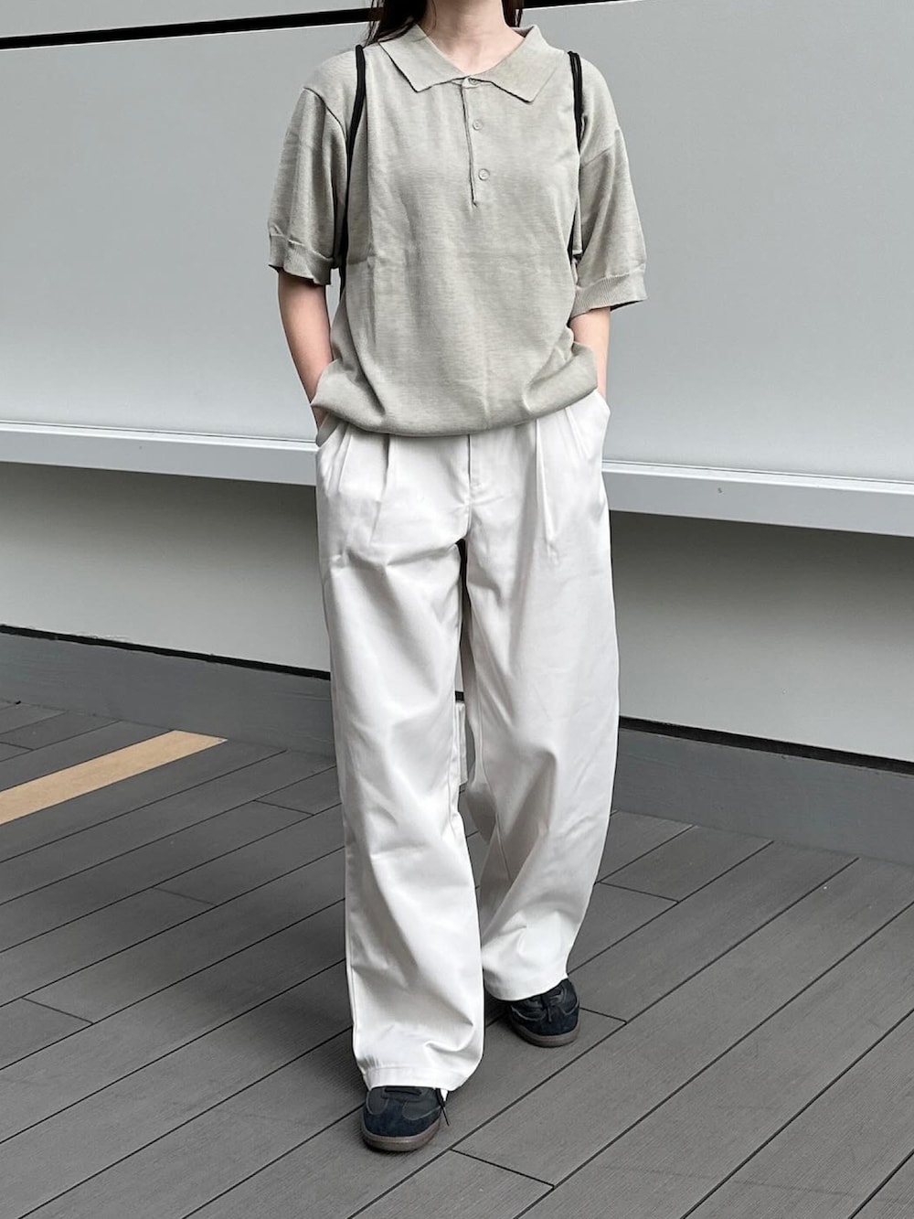 グレー系のポロシャツ、ホワイト系のチノパンツ、ブラック系のショルダーバッグを着用したレディースの夏コーディネートの2枚目の写真