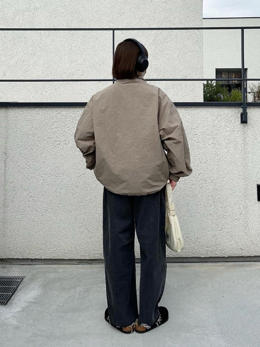 ベージュ系のブルゾン、ブラック系のデニムパンツ、ブラック系のサンダルを着用したレディースの秋コーディネートの3枚目の写真
