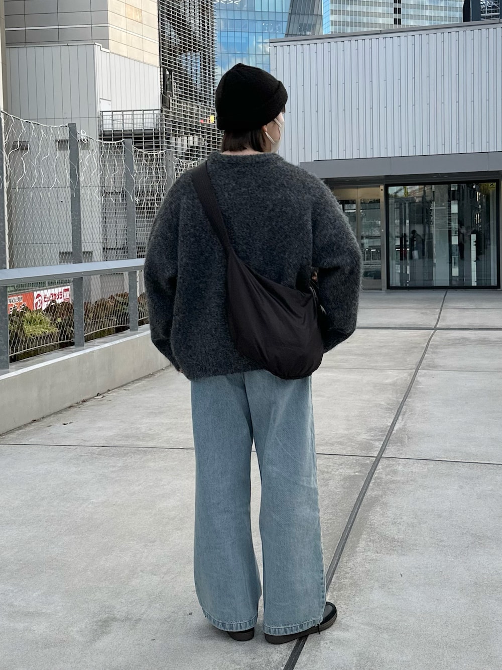 グレー系のニット/セーター、ブルー系のデニムパンツ、ブラック系のショルダーバッグを着用したレディースの冬コーディネートの2枚目の写真