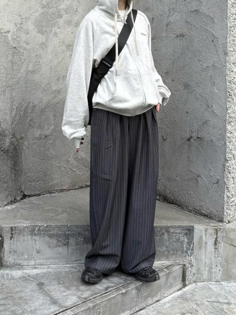 ブラック系のスニーカー、グレー系のパーカー、グレー系のスラックスを着用したレディースの春コーディネートの2枚目の写真