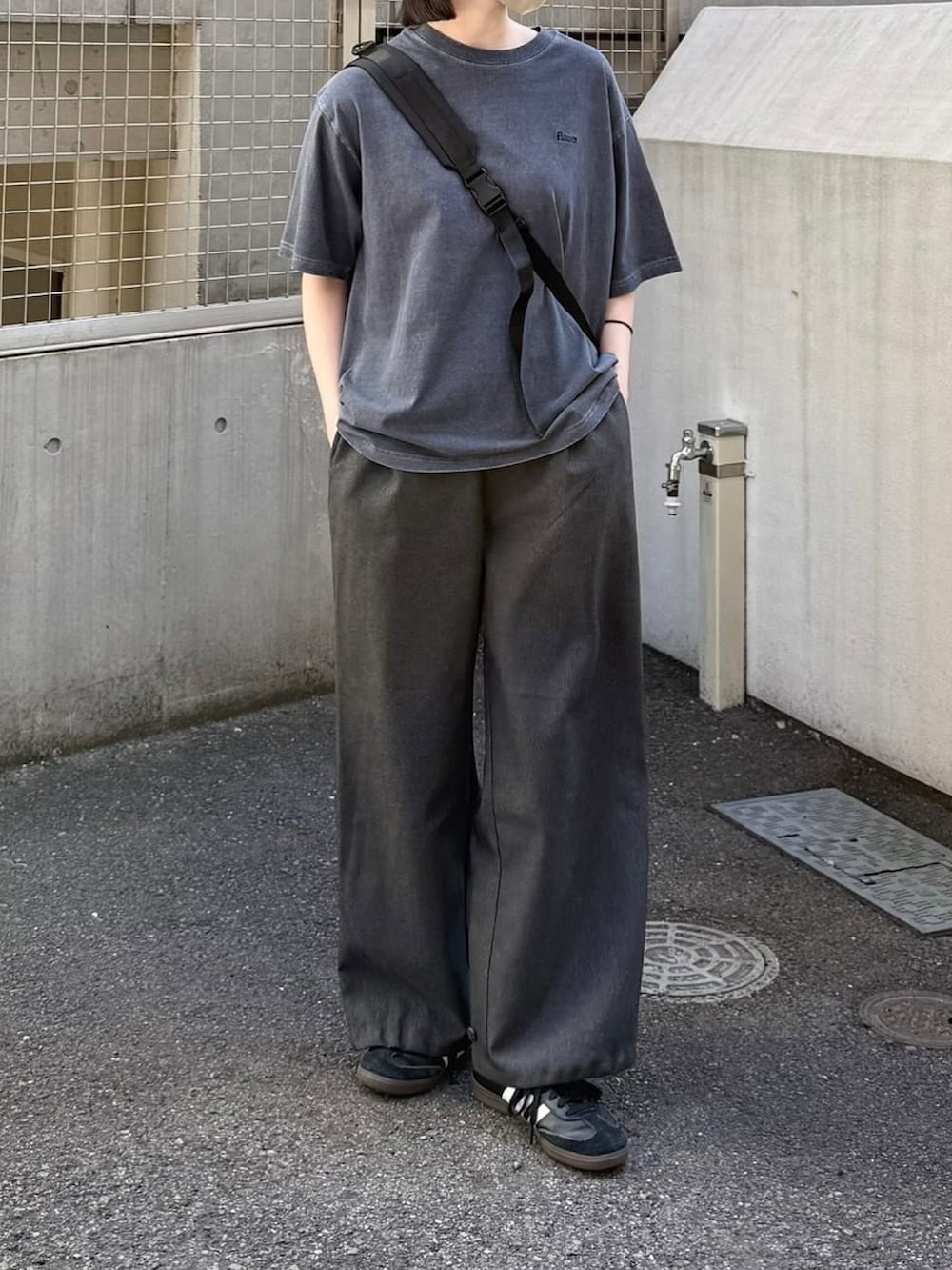 ブルー系のTシャツ/カットソー、グレー系のスラックス、ブラック系のショルダーバッグを着用したレディースの春コーディネートの2枚目の写真