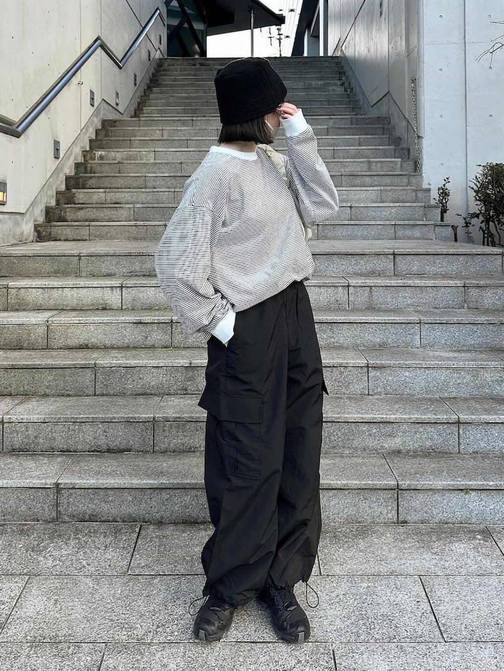 ホワイト系のTシャツ/カットソー、ブラック系のカーゴパンツ、ブラック系のスニーカーを着用したレディースの冬コーディネートの2枚目の写真