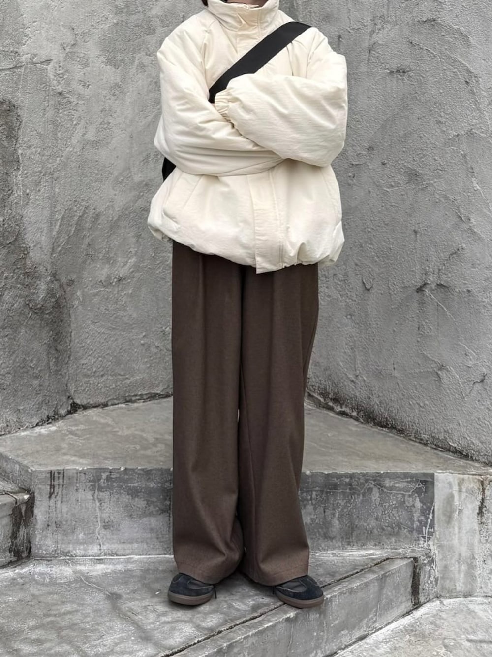 ホワイト系のその他アウター、ブラウン系のスラックス、ブラック系のショルダーバッグを着用したレディースの冬コーディネートの2枚目の写真