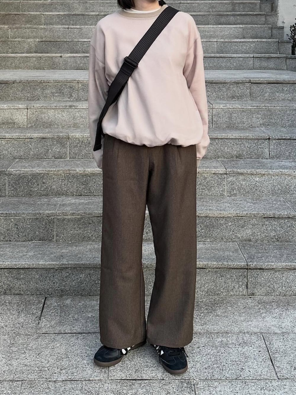 ベージュ系のTシャツ/カットソー、ブラウン系のスラックス、ブラック系のショルダーバッグを着用したレディースの春コーディネートの2枚目の写真