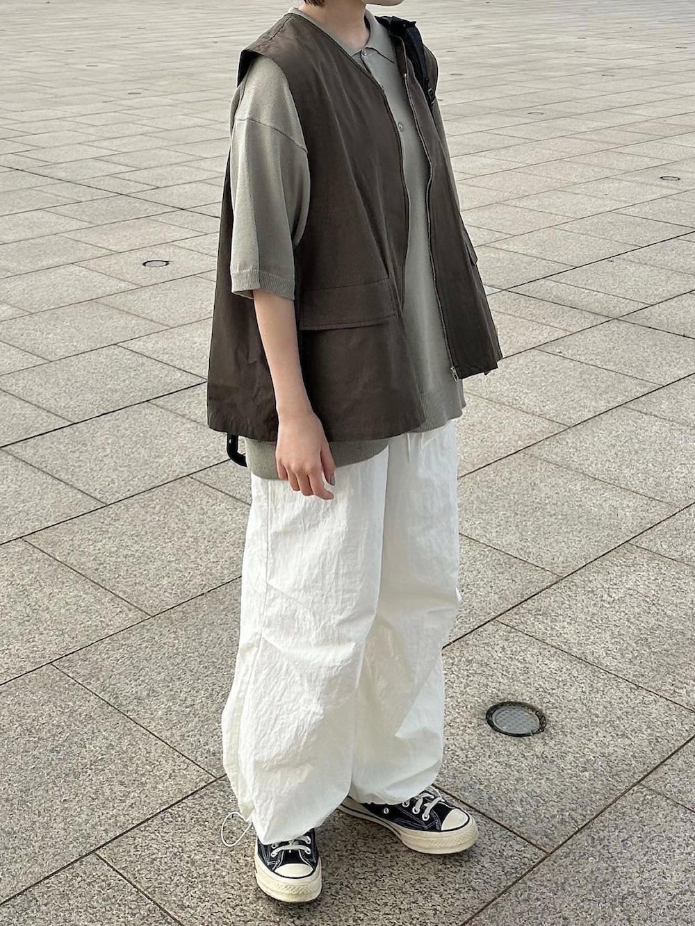 グレー系のベスト、ホワイト系のその他パンツ、ブラック系のバックパック/リュックを着用したレディースの春コーディネートの3枚目の写真