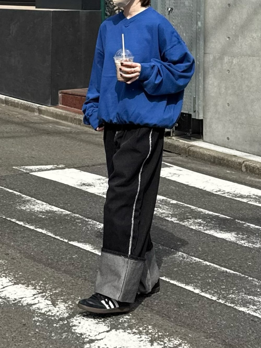 ブルー系のスウェット、ブラック系のデニムパンツ、ブラック系のスニーカーを着用したレディースの春コーディネートの2枚目の写真