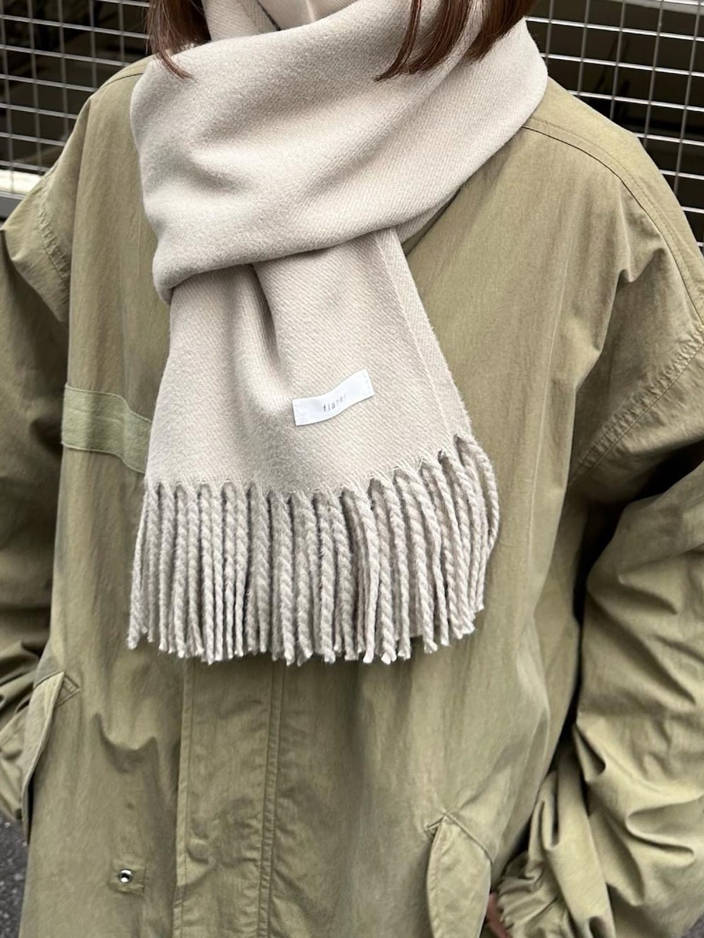 グリーン系のモッズコート、ブラック系のカーゴパンツ、ブラック系のスニーカーを着用したレディースの秋コーディネートの3枚目の写真