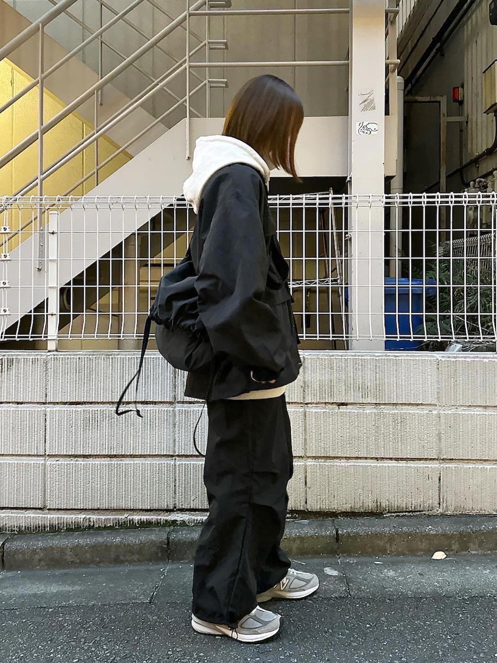 ブラック系のナイロンジャケット、グレー系のパーカー、ブラック系のその他パンツを着用したレディースの秋コーディネートの2枚目の写真