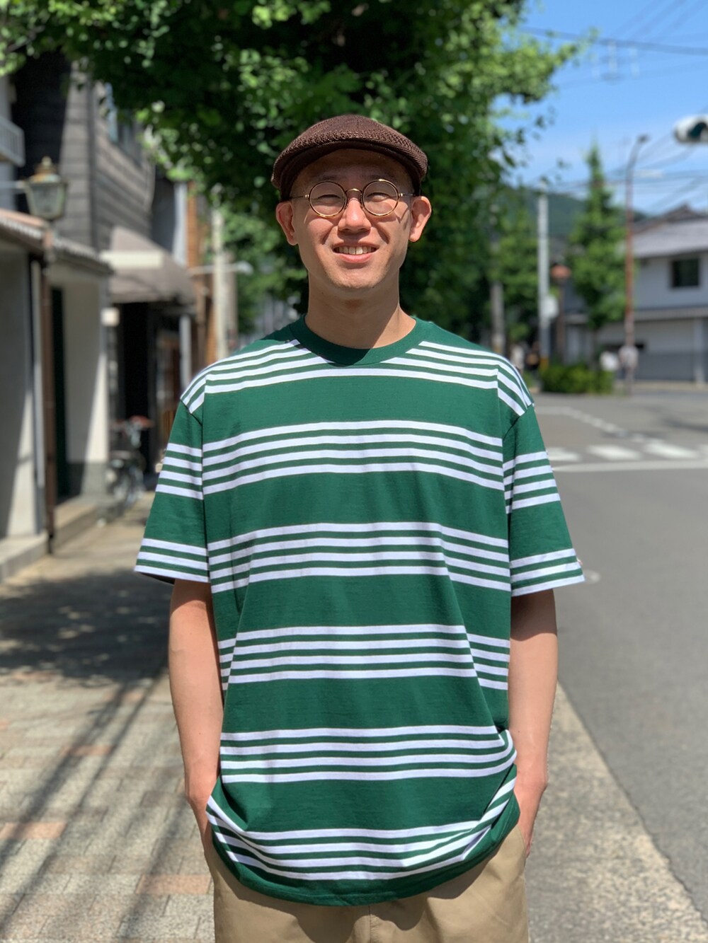 グリーン系のTシャツ/カットソー、ベージュ系のチノパンツ、ブラック系のスニーカーを着用したメンズの夏コーディネートの3枚目の写真