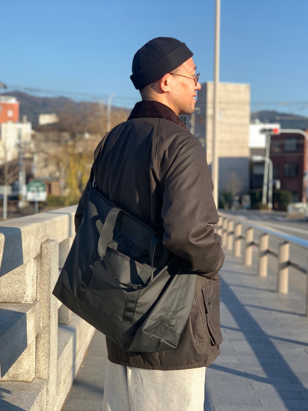 ブラウン系のジャケット/アウター、ブラック系のトートバッグ、グレー系のスウェットパンツを着用したメンズの冬コーディネートの5枚目の写真